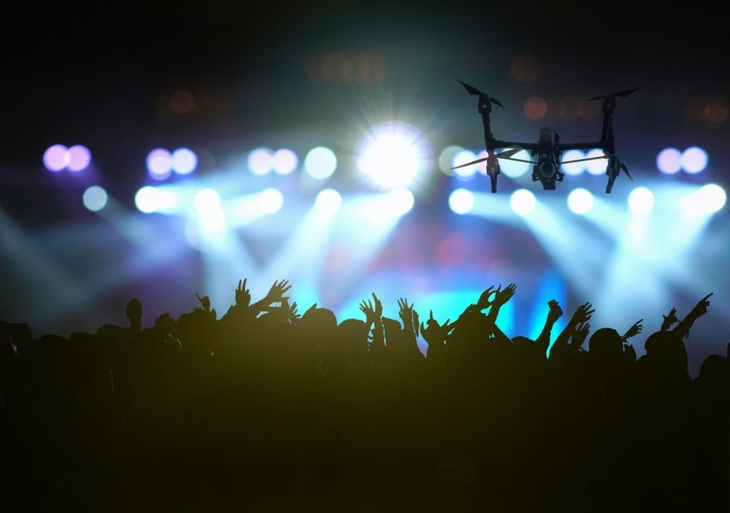 Closeup silhouette of Drone flying for taking video of Concert crowd